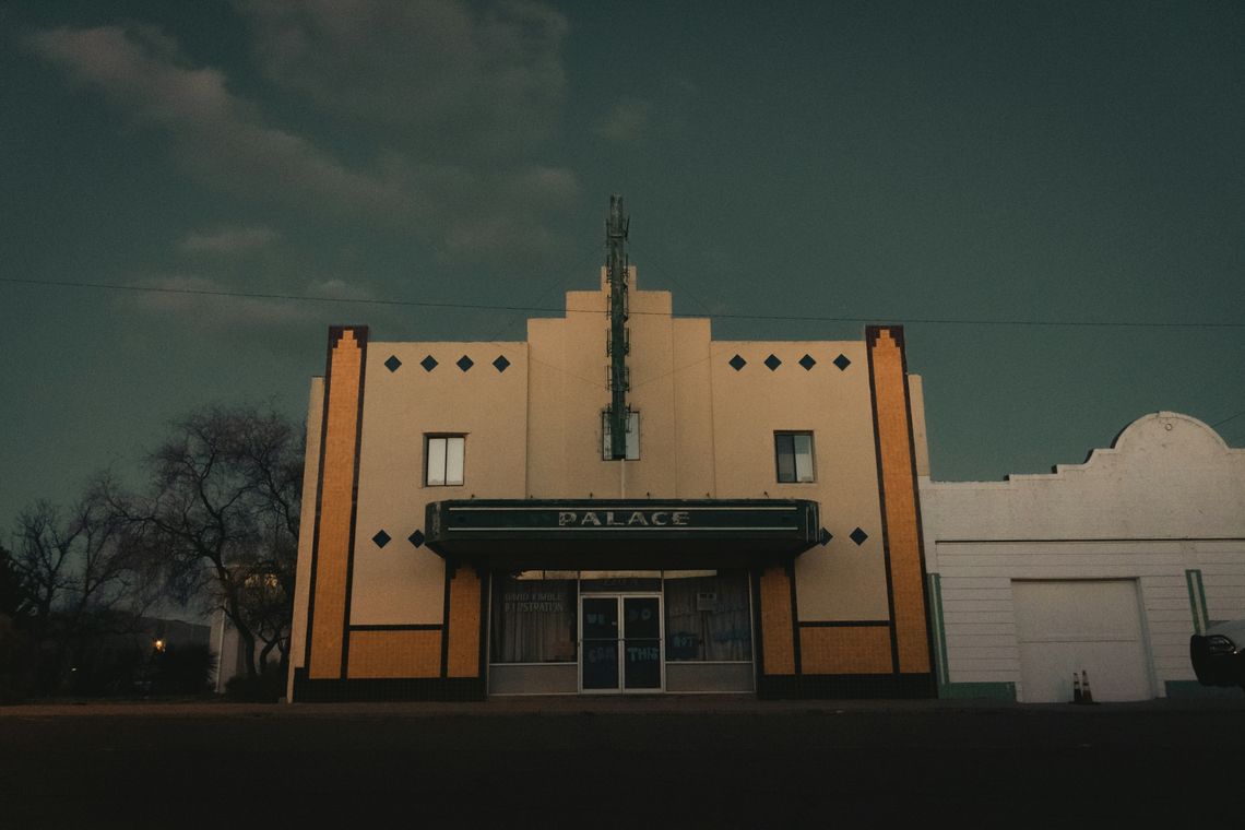 An old theater building in Texas with a dark sky behind it.